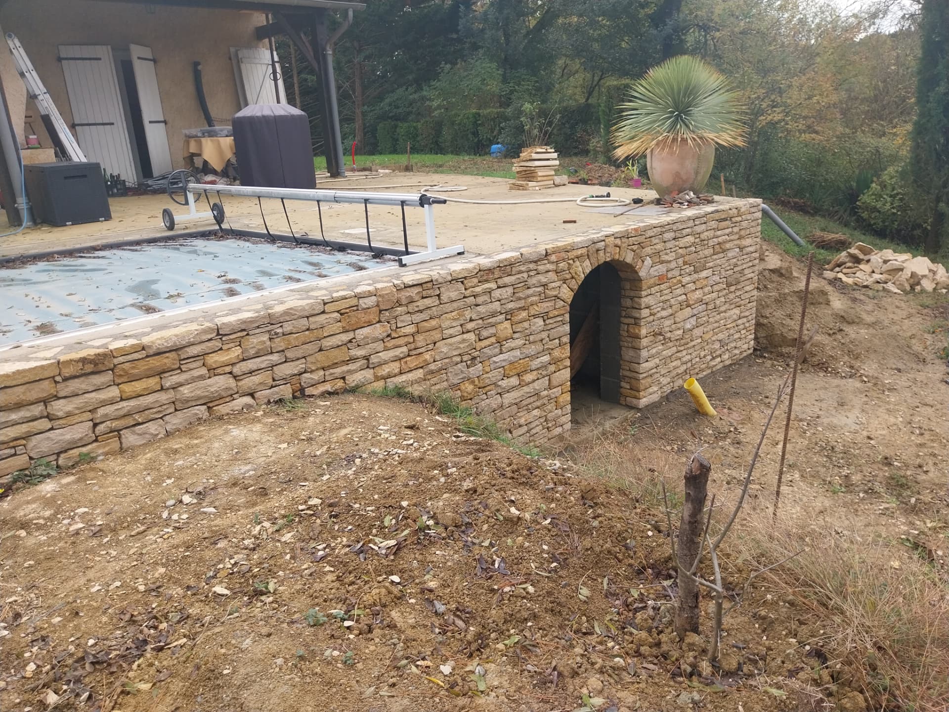 Piscine semi-enterrée en Pierre du Lot avec porte cintrée