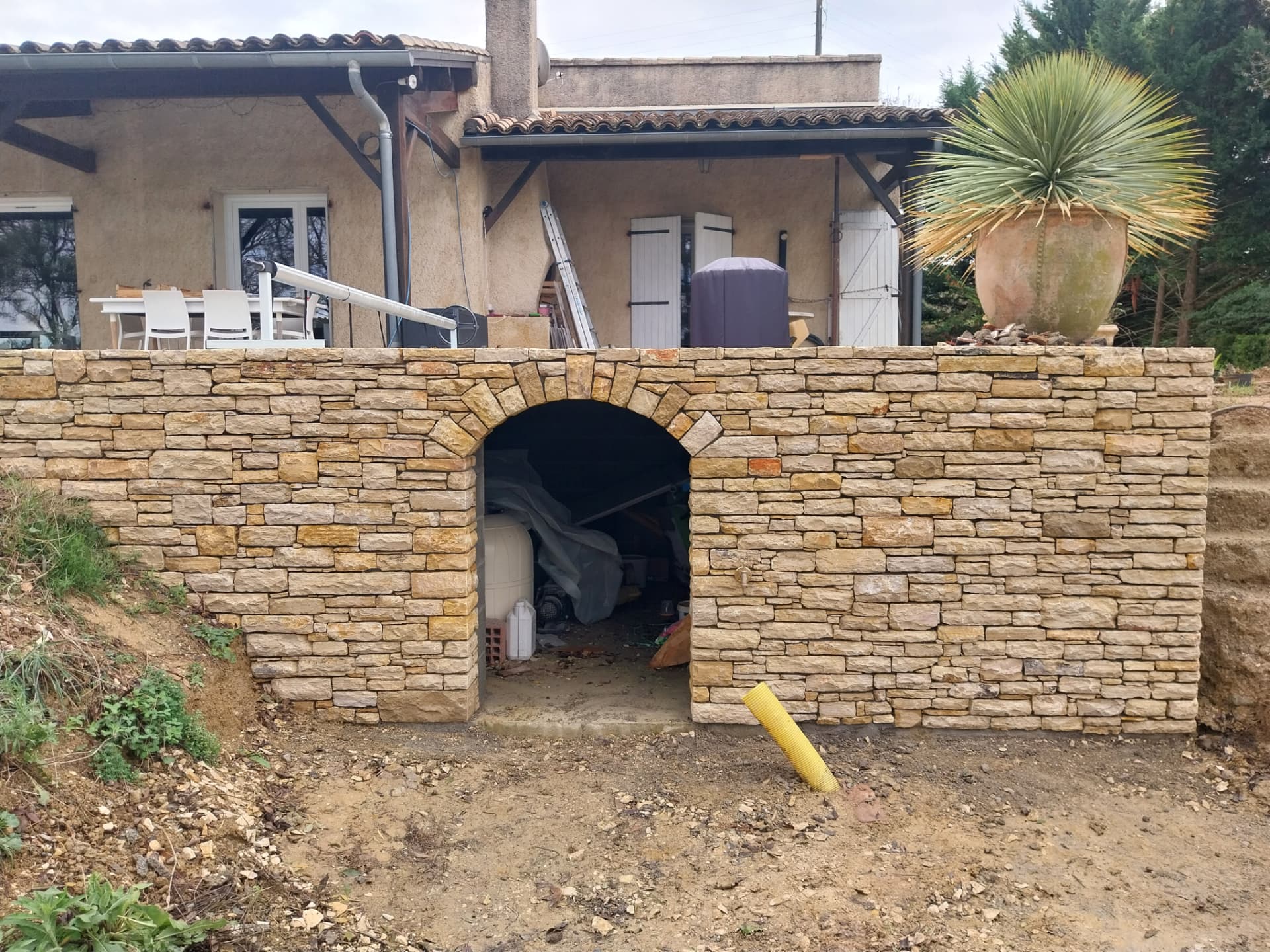 Piscine semi-enterrée en Pierre du Lot avec porte cintrée